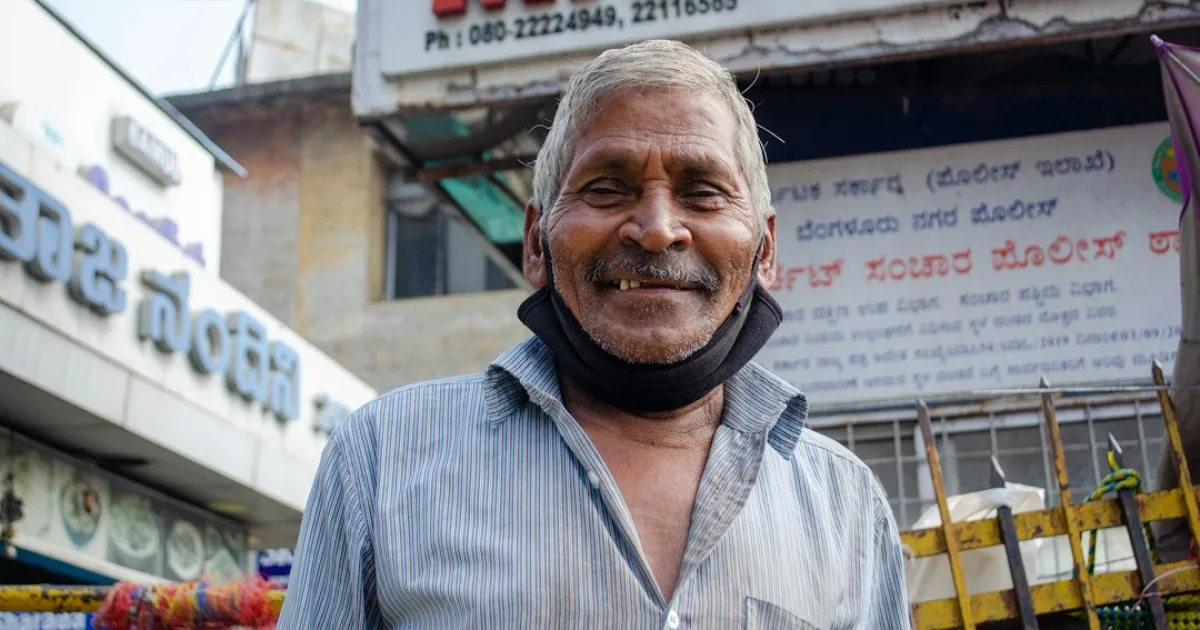 Small shop owner standing at the entrance of a shop on a busy Indian market street
